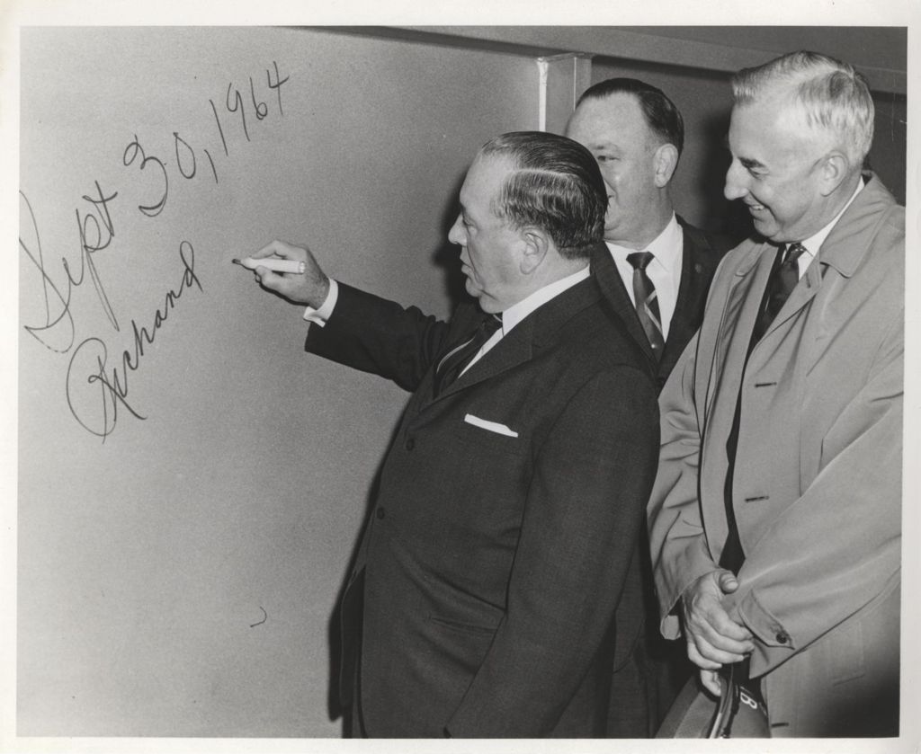 Richard J. Daley signing his name on a wall