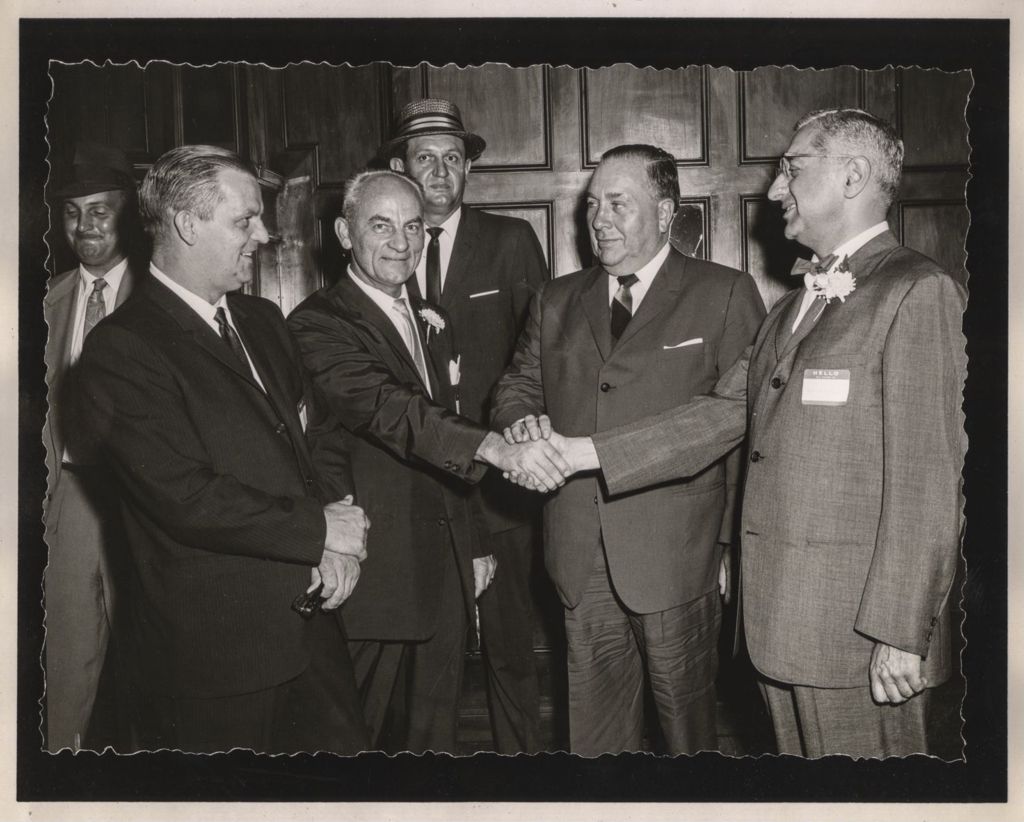 Friendship Banquet photo album, Richard J. Daley clasps hand with two men