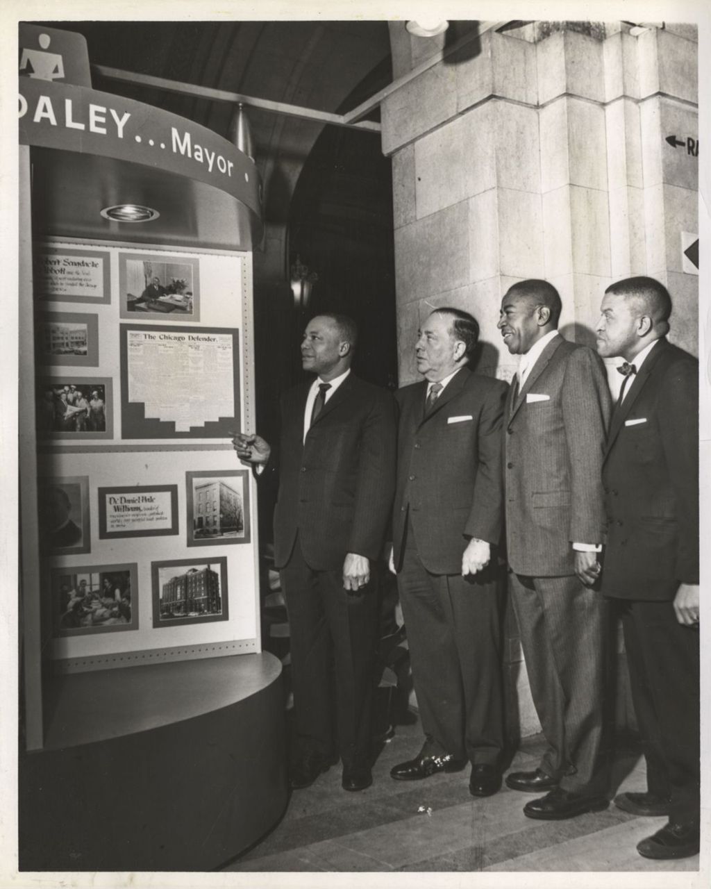 Richard J. Daley and three men view a Chicago Defender display