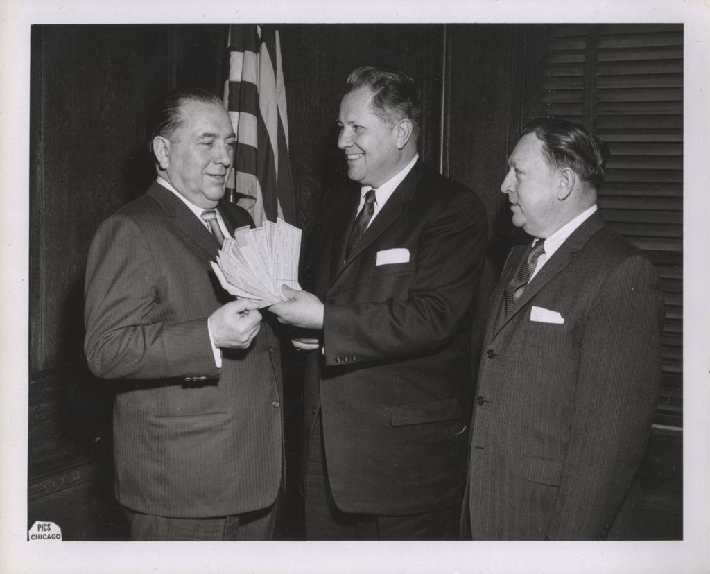 Miniature of Richard J. Daley accepting a bundle of checks from two men