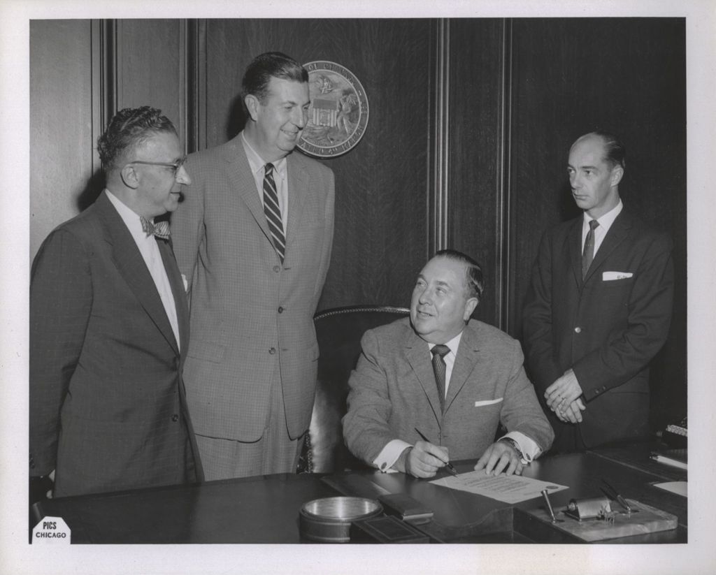 Miniature of Mayor Richard J. Daley signs a document at his desk