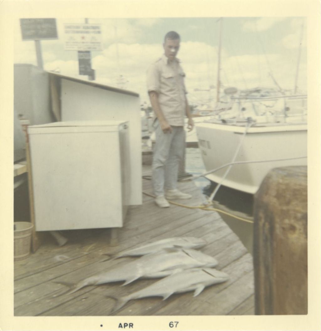 Man standing next to three fish displayed on a dock