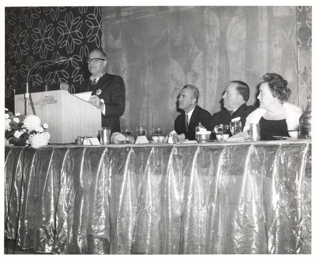 Richard J. and Eleanor Daley listen to a man speaking at a banquet