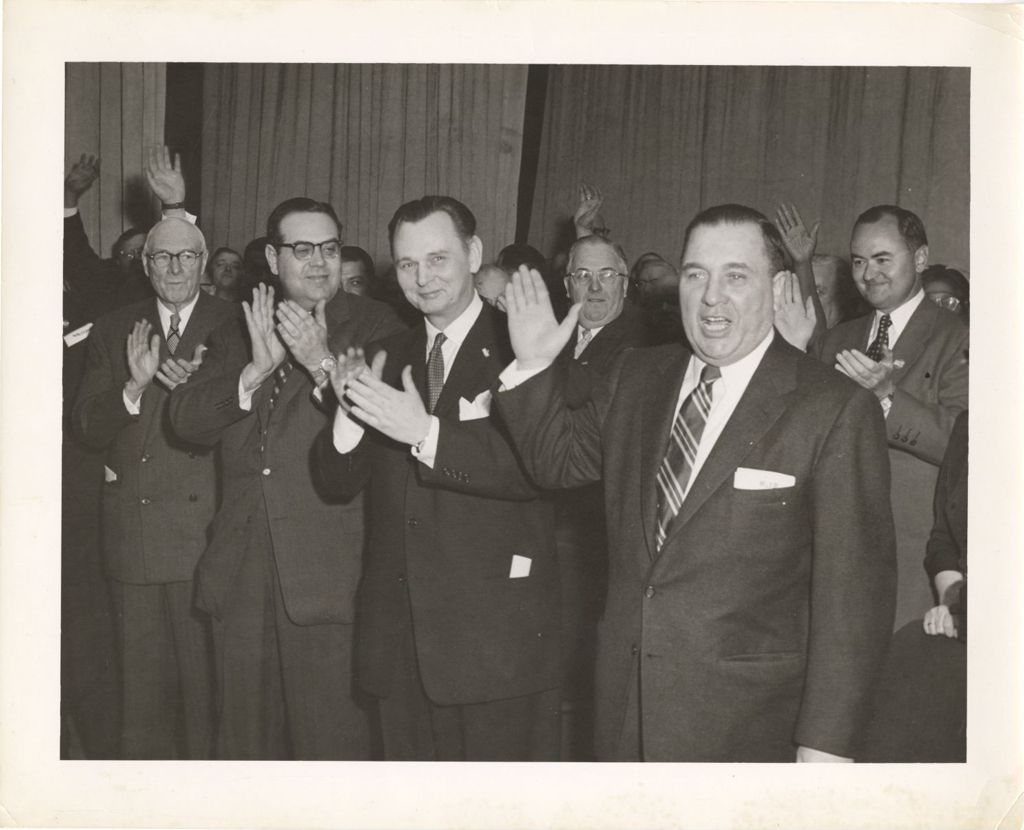 Miniature of Richard J. Daley raises his hand in a group of applauding people