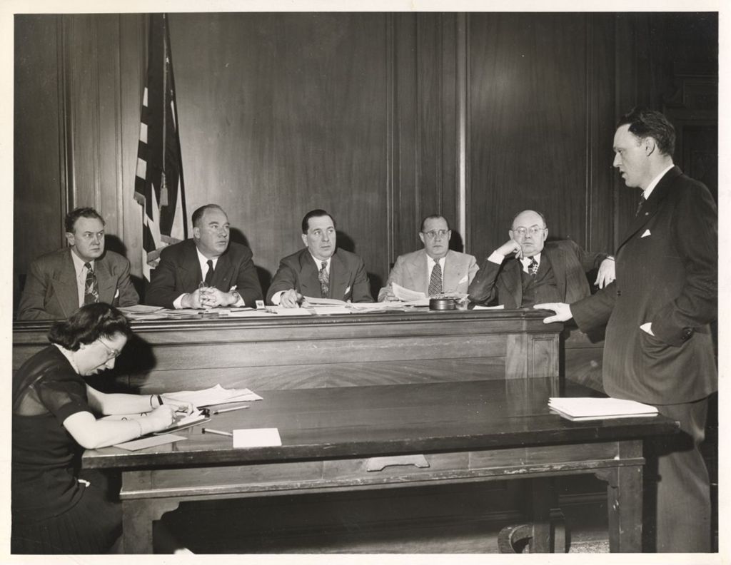 Miniature of Richard J. Daley seated with a group of men [in a courtroom?]
