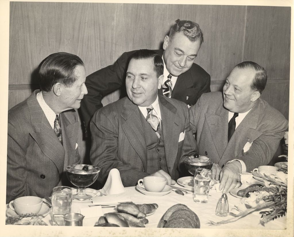 Richard J. Daley seated at a banquet table with two others
