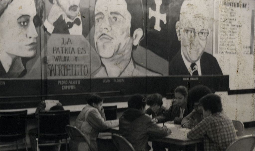 Miniature of Students sitting at a table beneath murals of political figures