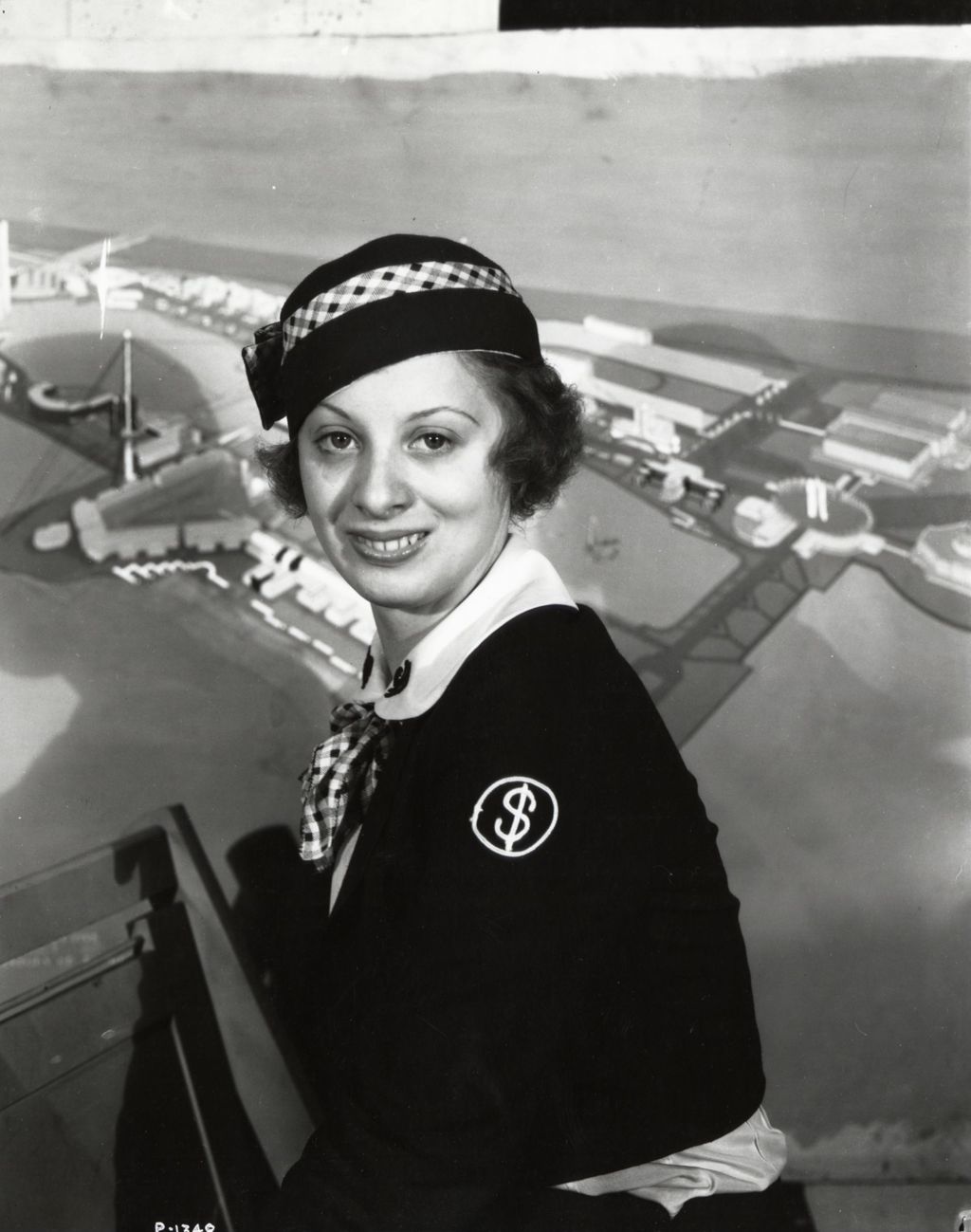 Miniature of Miss Sonny Lundstrom, cashier, poses in uniform in front of a panorama of A Century of Progress