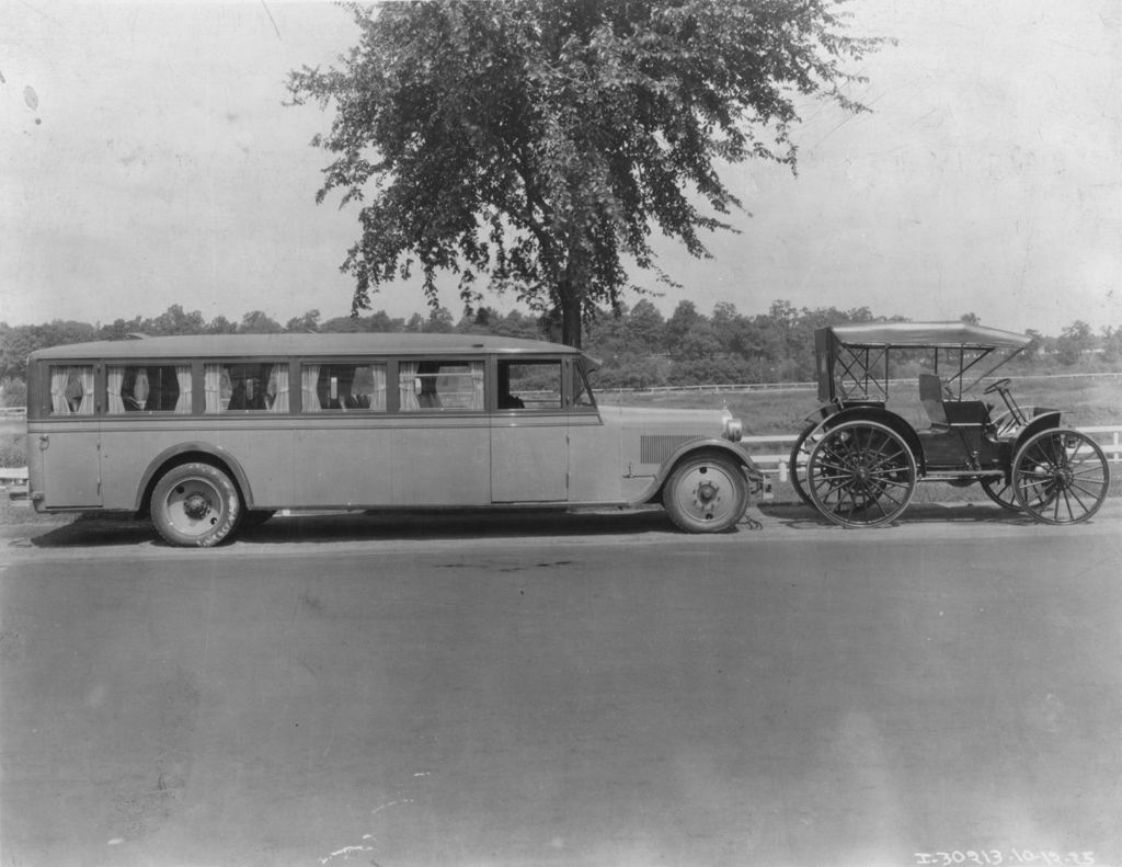 Bus parked behind a prototype to Henry Ford's popular Model T automobile