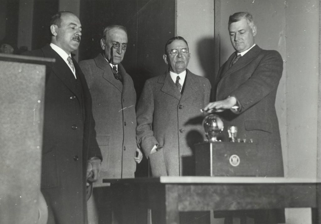 Miniature of W.O. Batchelder, president of the Electric Association of Chicago, passing his hand over a grid-glow tube to activate lights at Electrical Group's dedication ceremony