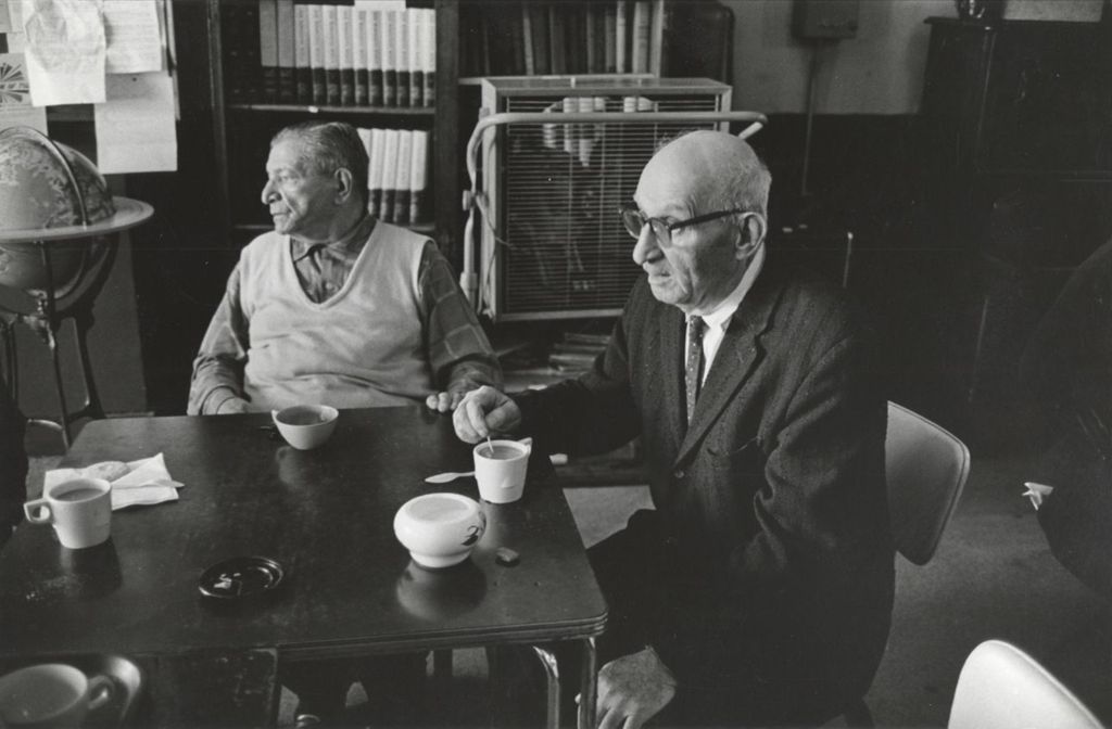 Two senior men sitting at a table with coffee