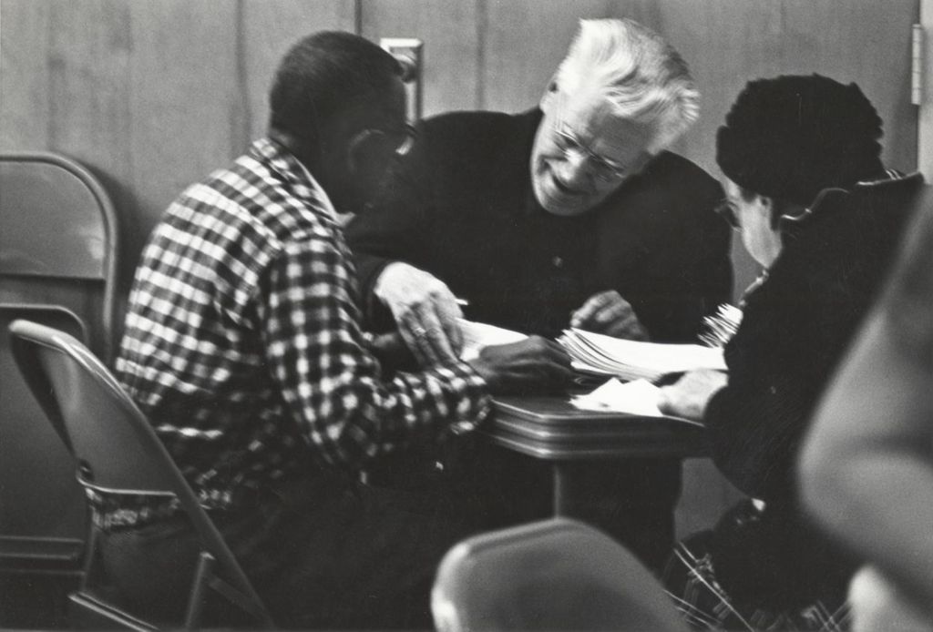 Three seniors at a table with folded papers at the Conrad Senior Center