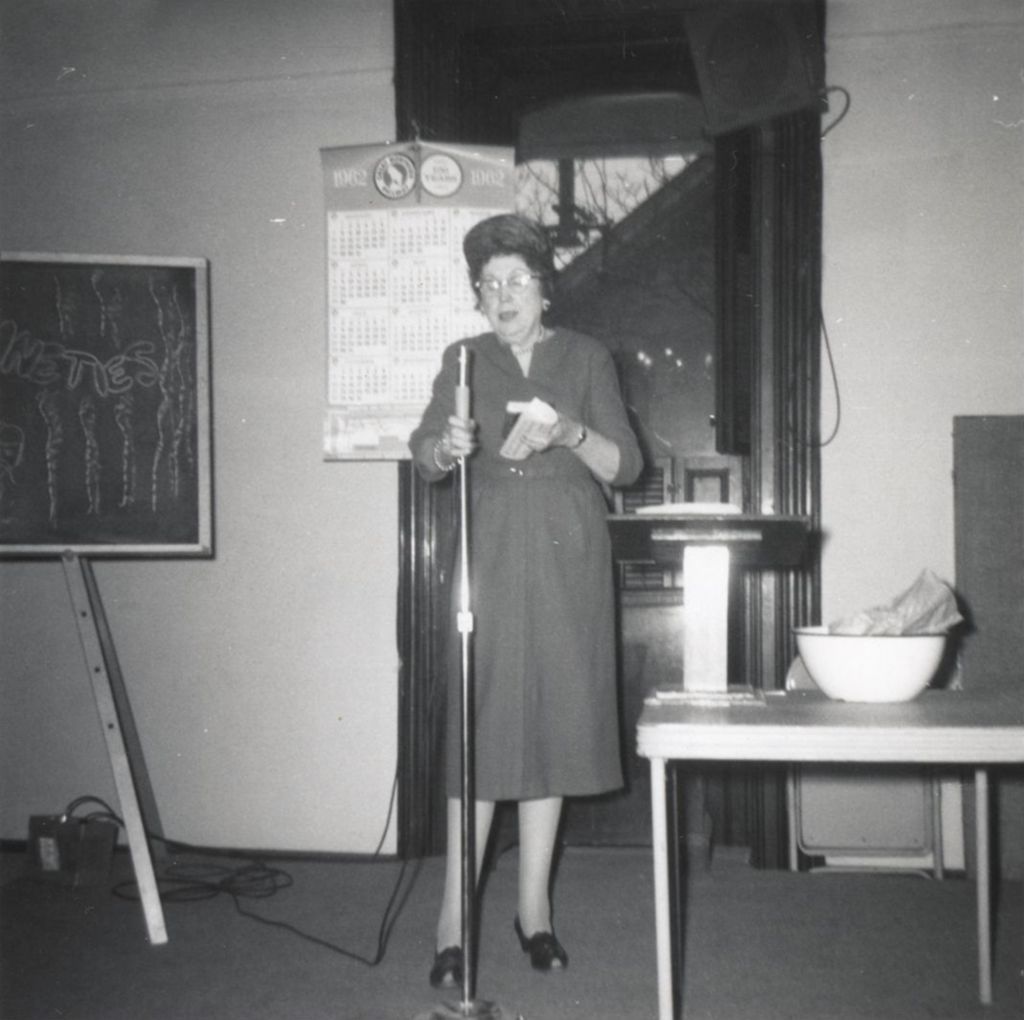 Woman talking into a microphone at an event at Hull-House or a senior center affiliated with Hull-House