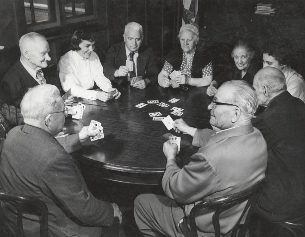 Ten men and women, members of the Hull-House senior citizens group, playing cards around a round table