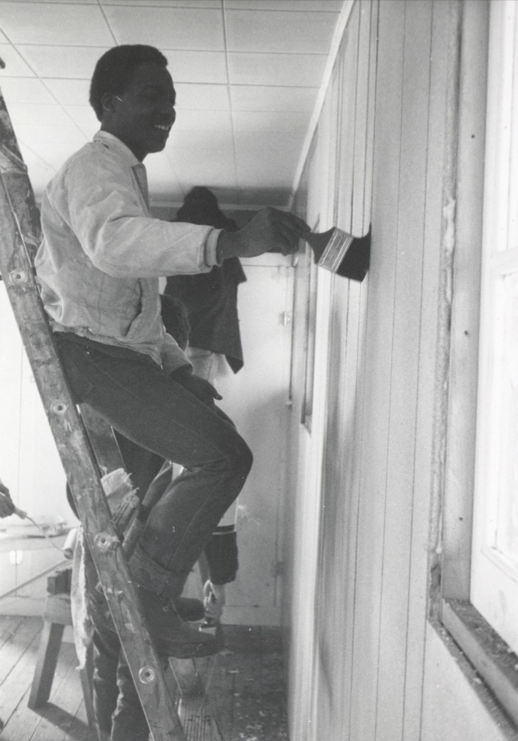 Young man applies varnish to a wall in a room at the Hull-House camp in Wisconsin