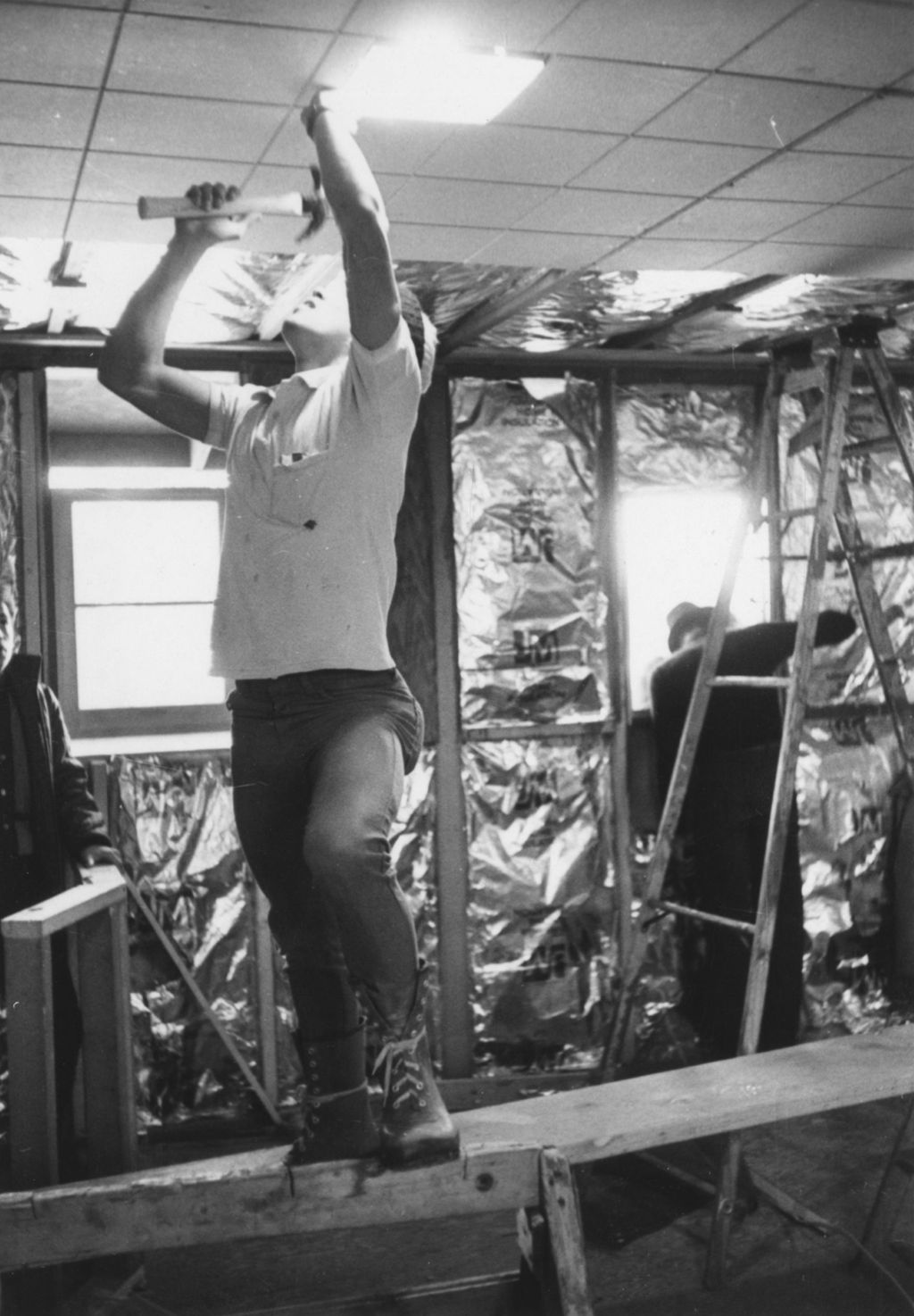 Young man hammering into the ceiling at the Hull-House camp in Wisconsin