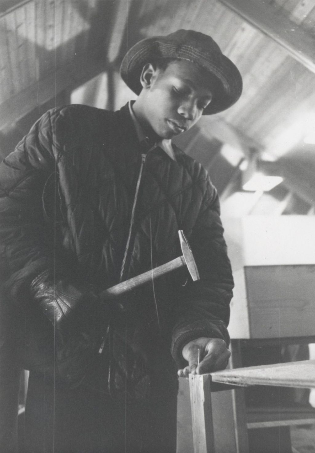 Young man hammering a nail at the Hull-House camp in Wisconsin