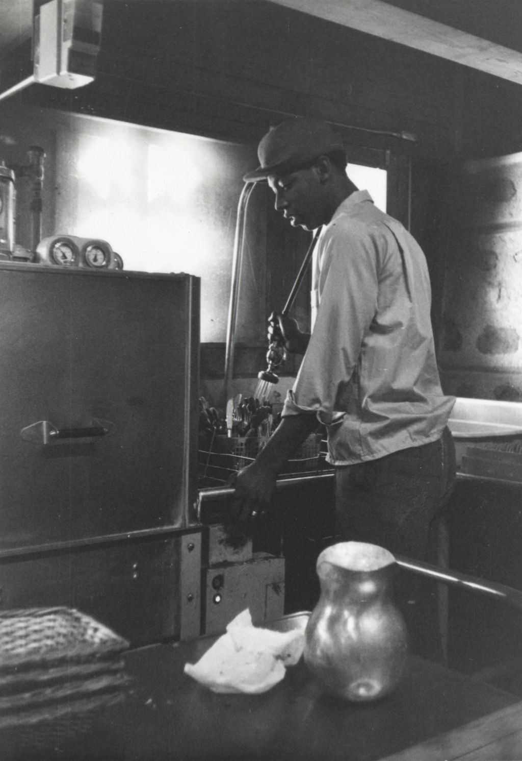 Young man rinsing silverware in the kitchen at the Hull-House camp in Wisconsin