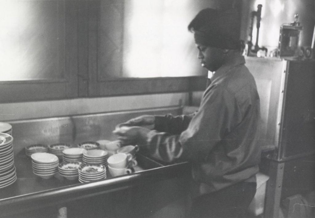 Young man stacking dishes in the kitchen at the Hull-House camp in Wisconsin