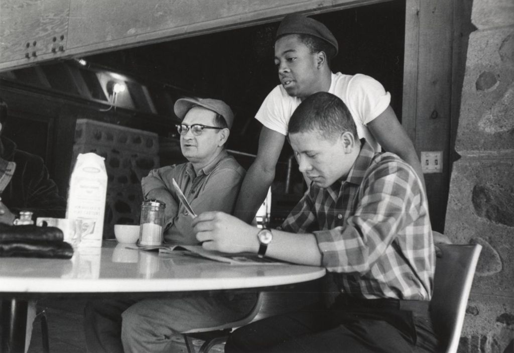 A man and two young men at a table at the Hull-House camp in Wisconsin