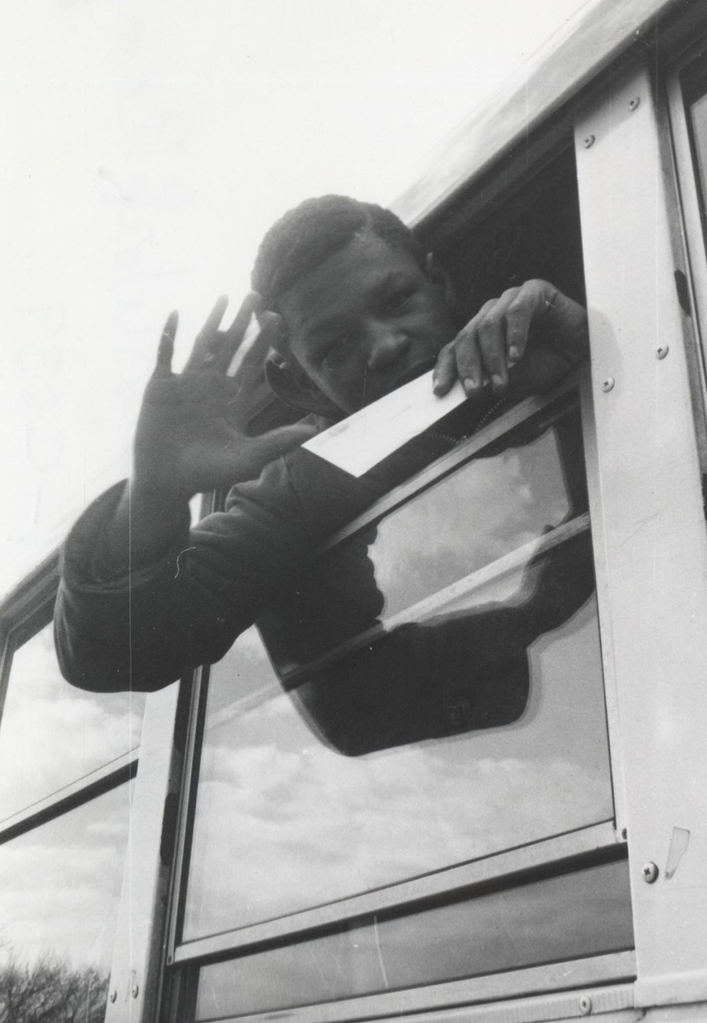 Young man leaning out and waving from the window of a bus at the Hull-House camp in Wisconsin