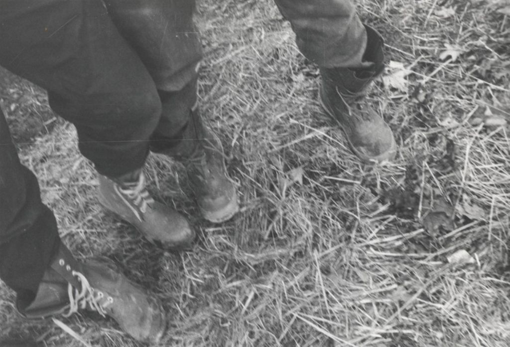 Legs of two people standing on straw at Hull-House camp in Wisconsin