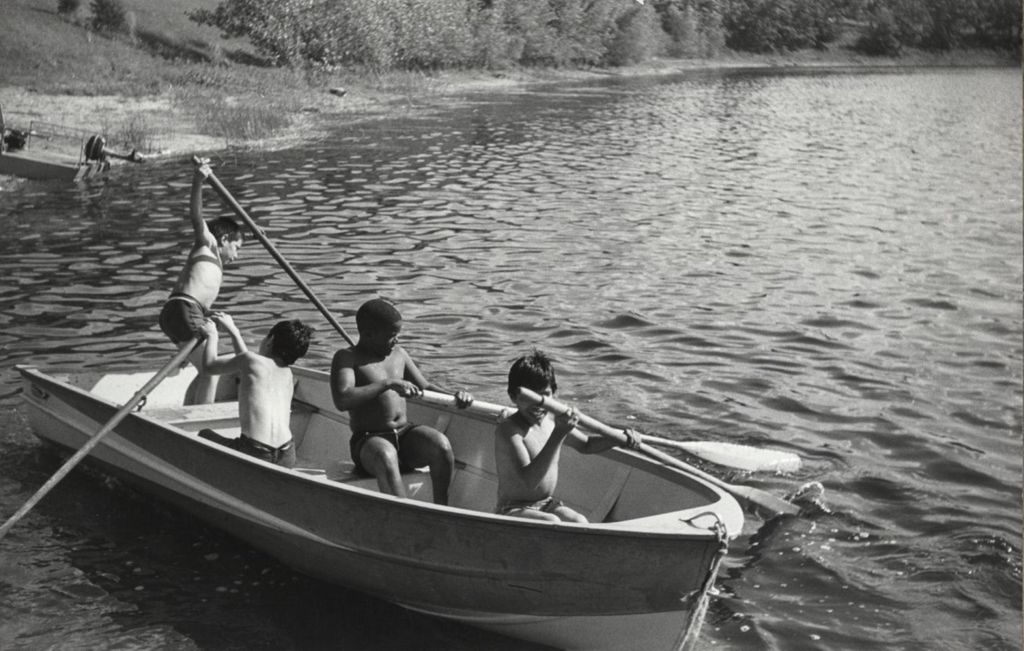 Four boys rowing a boat in a lake at the Hull-House camp in Wisconsin