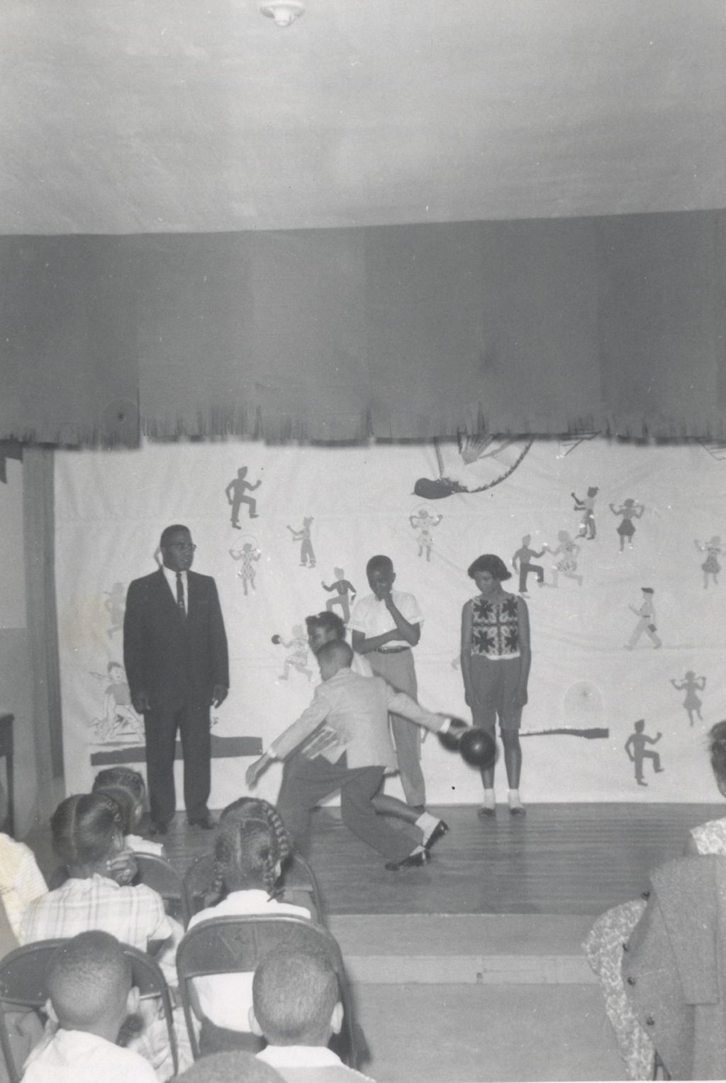 Two young people demonstrate bowling technique on stage at an event at Parkway Community House