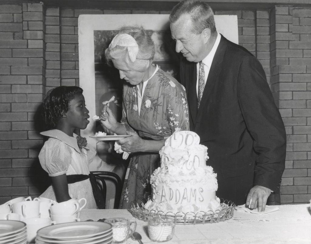 Jane Addams' grand niece feeds a bite of cake celebrating the centennial of Addams' birth to a girl as the president of the Hull-House board looks on