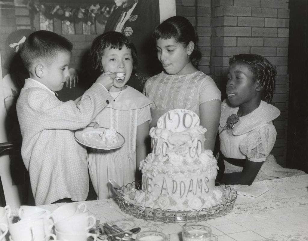 Miniature of A boy feeds a piece of cake celebrating the centennial of Addams' birth to a girl as two other children look on