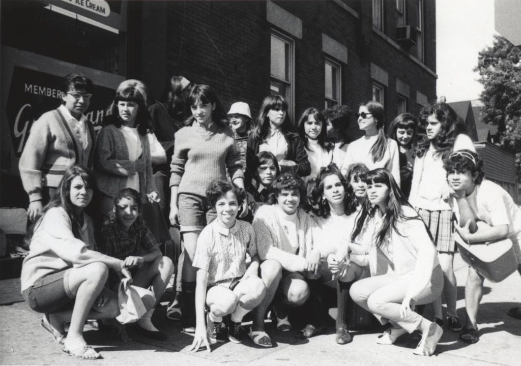 Miniature of Around 21 young women gathered for a "spring activity," posing next to a grocery store, likely near the Hull-House Jane Addams Center