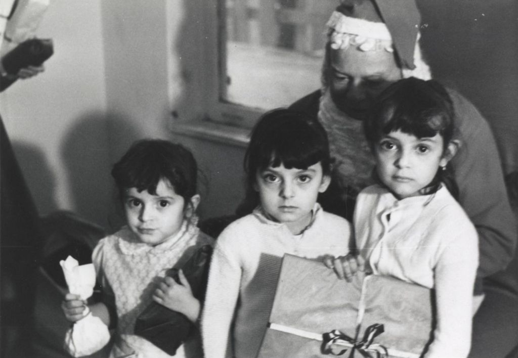 Santa Claus and three girls with gifts at a Hull-House Christmas party at Jane Addams Center