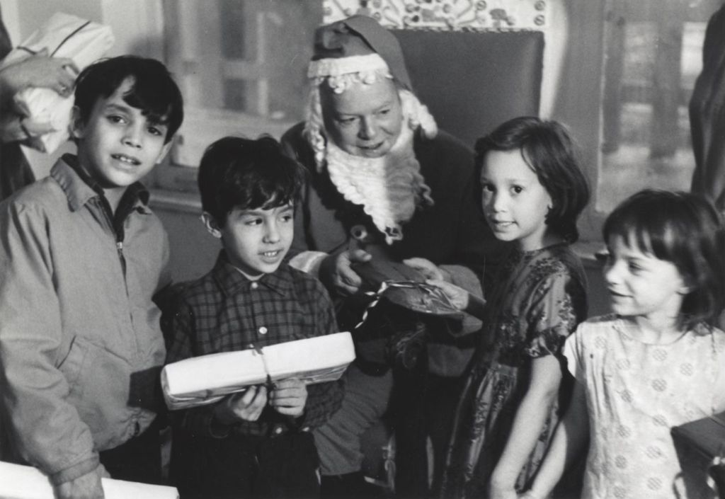 Santa Claus distributing gifts to children at a Hull-House Christmas party at Jane Addams Center