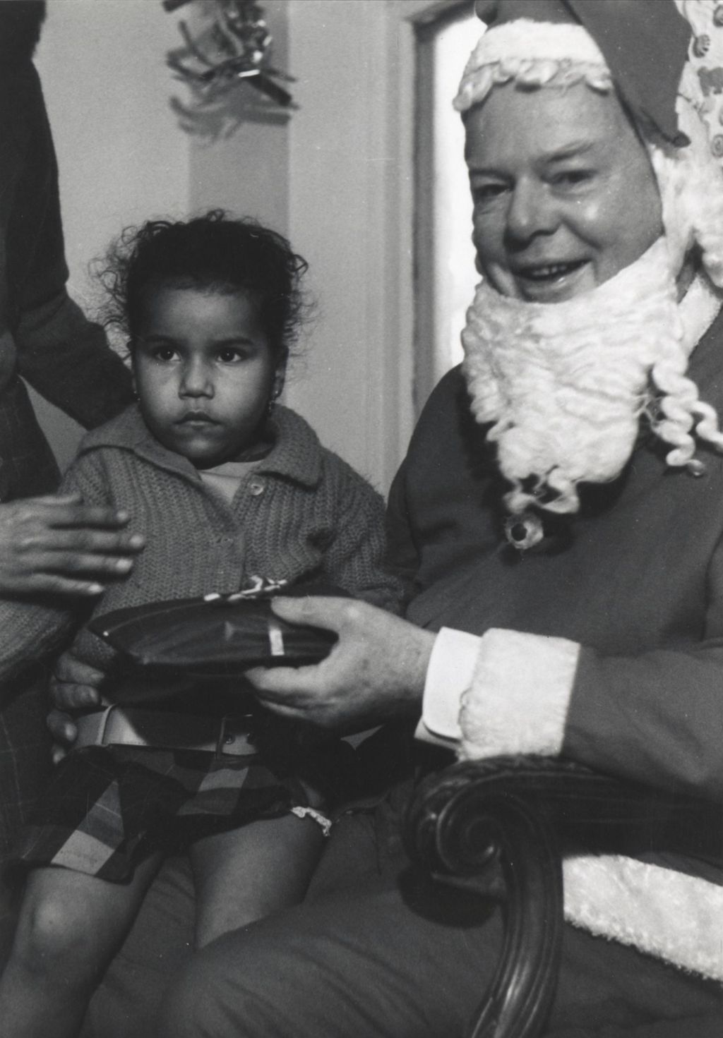 Girl on Santa Claus' lap at a Hull-House Christmas party at Jane Addams Center