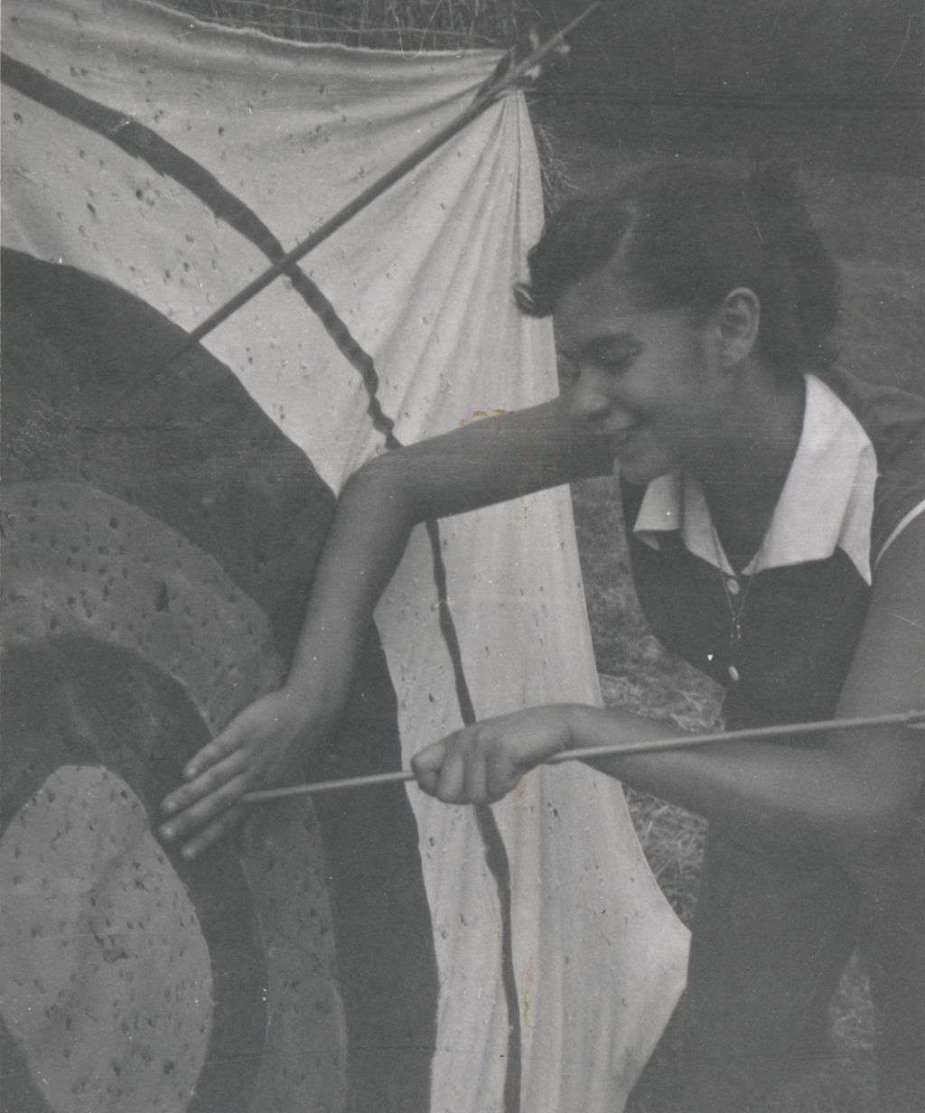 Pulling arrow from archery target, facing left