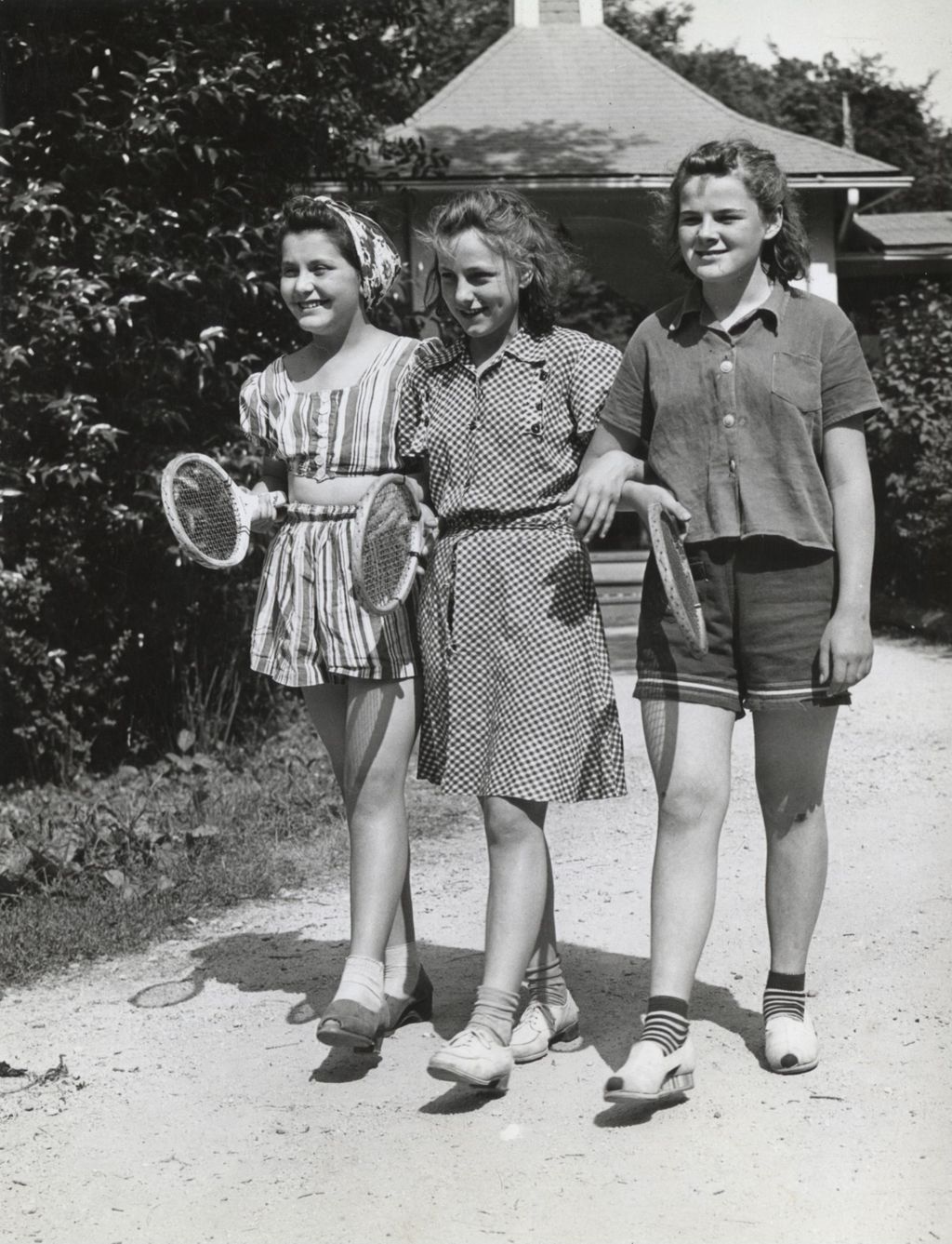 Three girls with tennis rackets walking