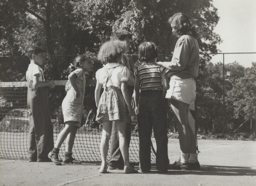 Children and teenage girl standing by tennis net