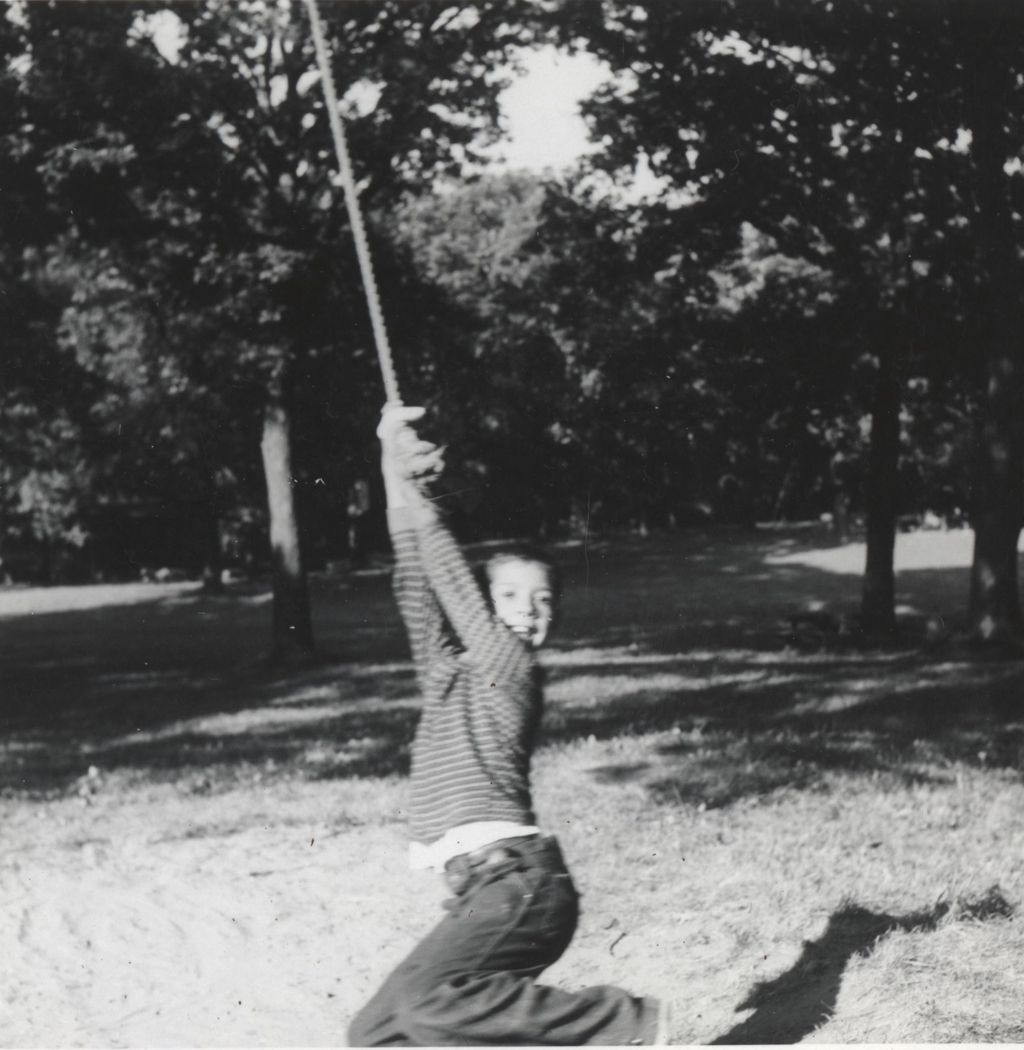 Boy hanging from rope swing at Camp French