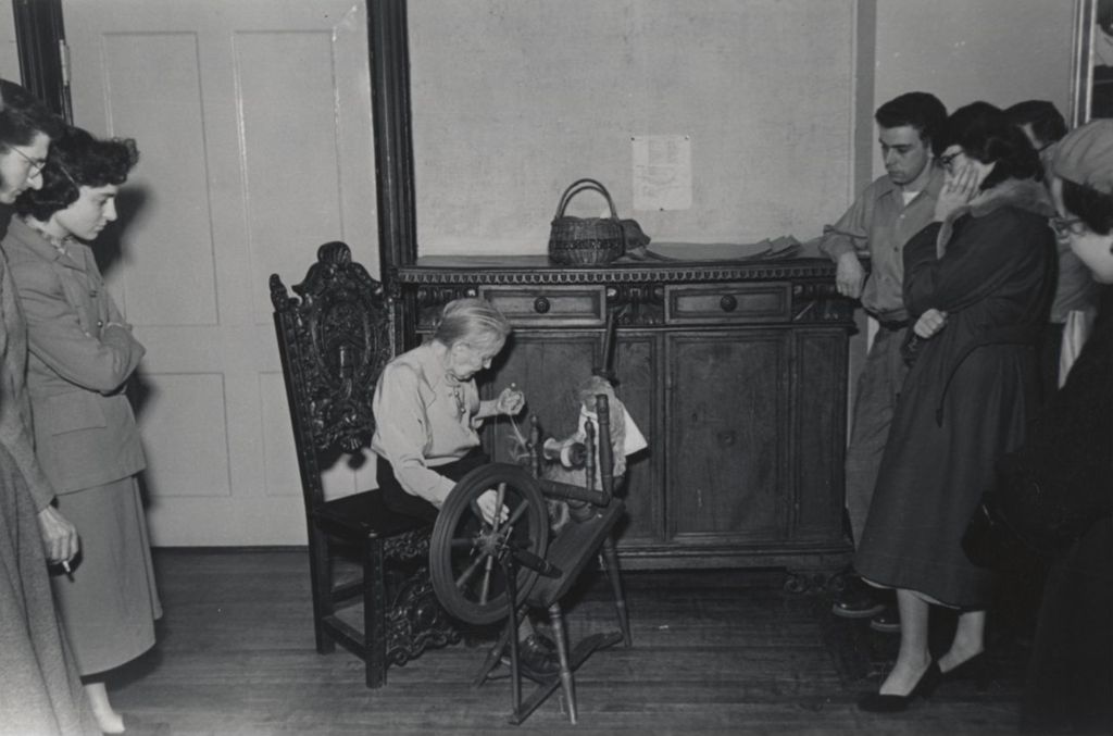 Woman demonstrating a spinning wheel to attendees during Hull-House 1951 Spring Carnival