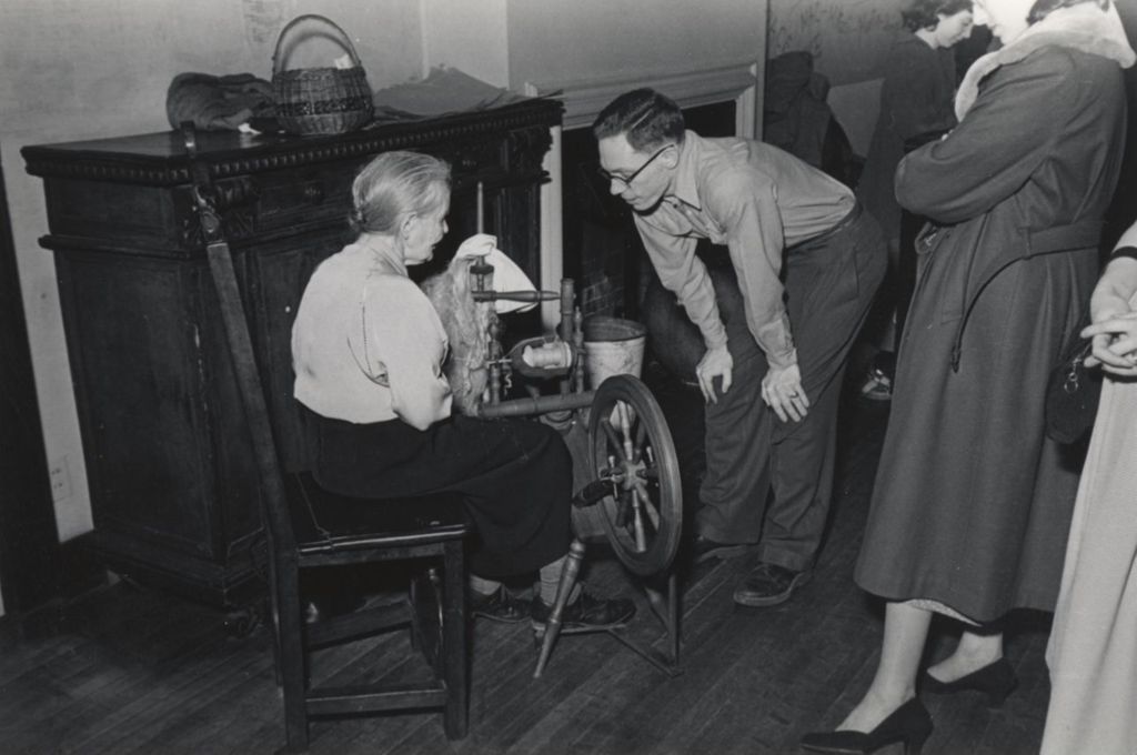 Woman demonstrating a spinning wheel to attendees during Hull-House 1951 Spring Carnival