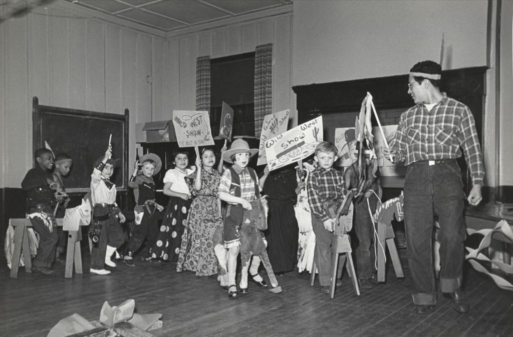 Miniature of Hull-House instructor Francis Solis leads a group of costumed children in a "Wild West Show" parade during the 1951 Spring Carnival