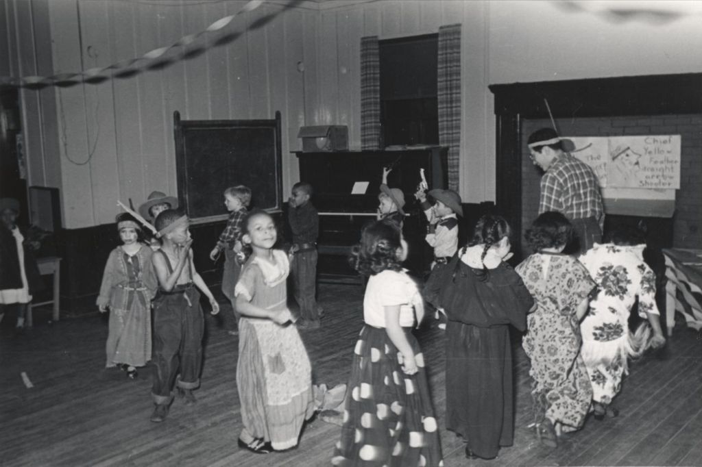 Miniature of Hull-House instructor Francis Solis and a group of costumed children walk in a circle for a "Wild West Show" during the 1951 Spring Carnival