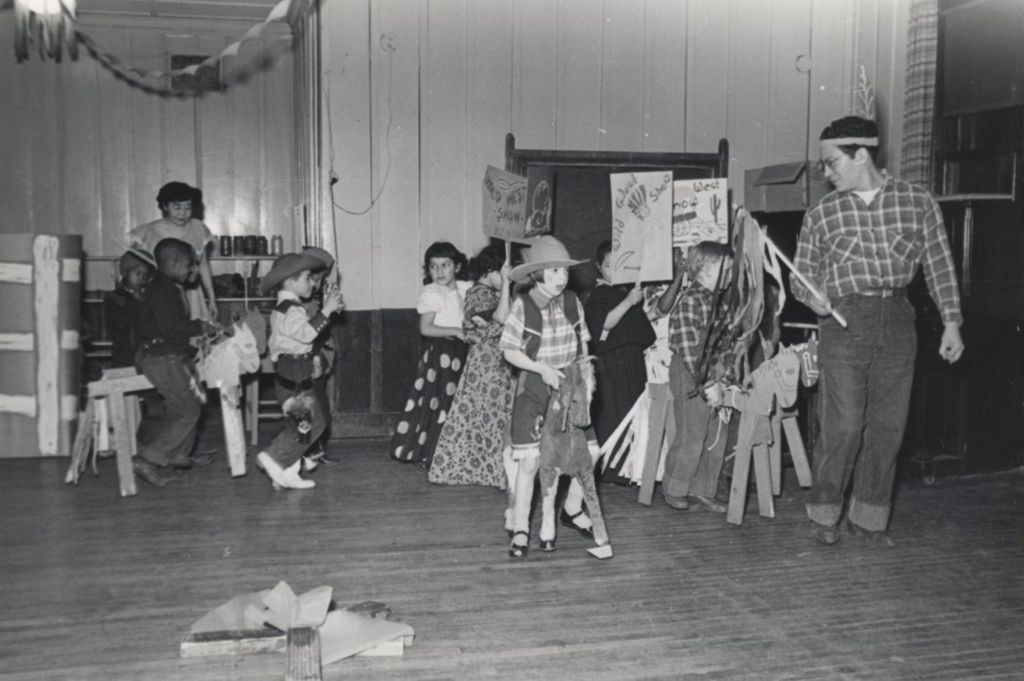 Hull-House instructor Francis Solis leads a group of costumed children in a "Wild West Show" parade during the 1951 Spring Carnival