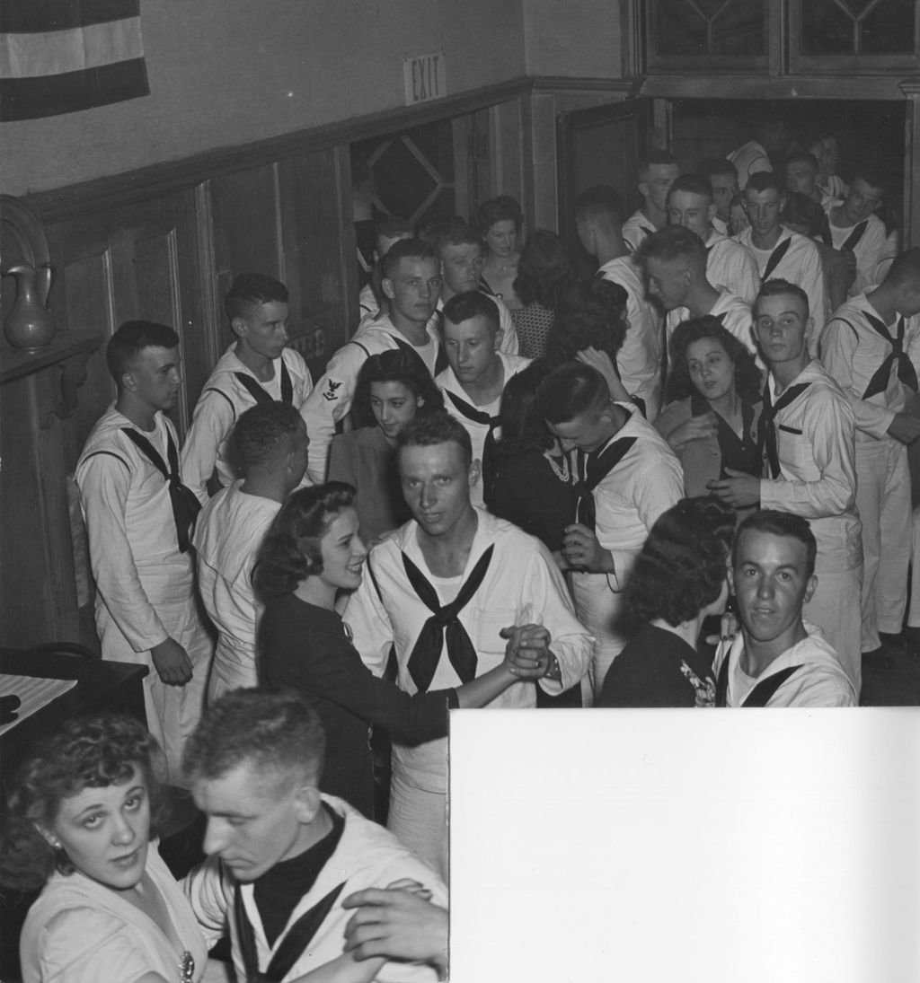 United States Navy sailors and civilian women dancing in pairs and socializing in the Hull-House Residents' Dining Hall during an "Entertaining the Navy" event