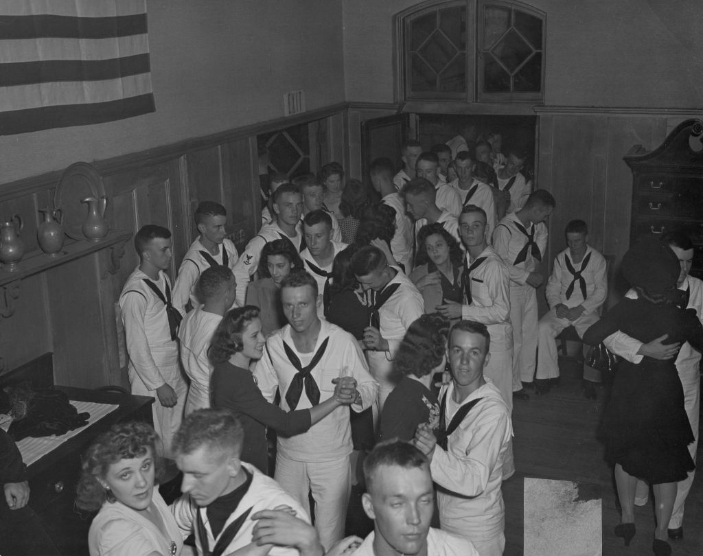 United States Navy sailors and civilian women dancing in pairs and socializing in the Hull-House Residents' Dining Room during an "Entertaining the Navy" event