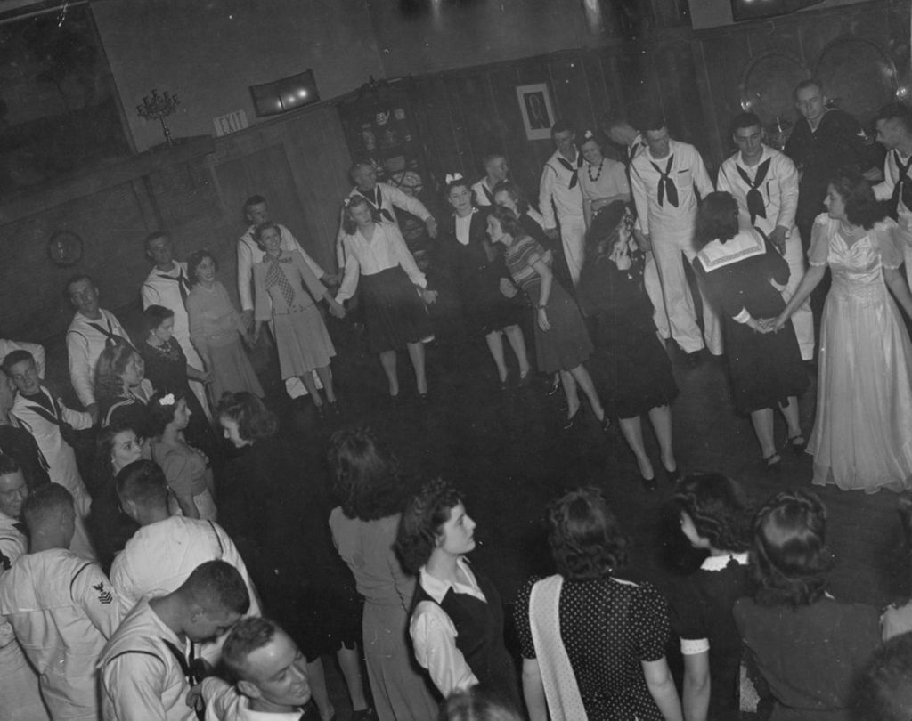 Young women and United States Navy sailors in large circles in the Hull-House Residents' Dining Hall during an "Entertaining the Navy" event