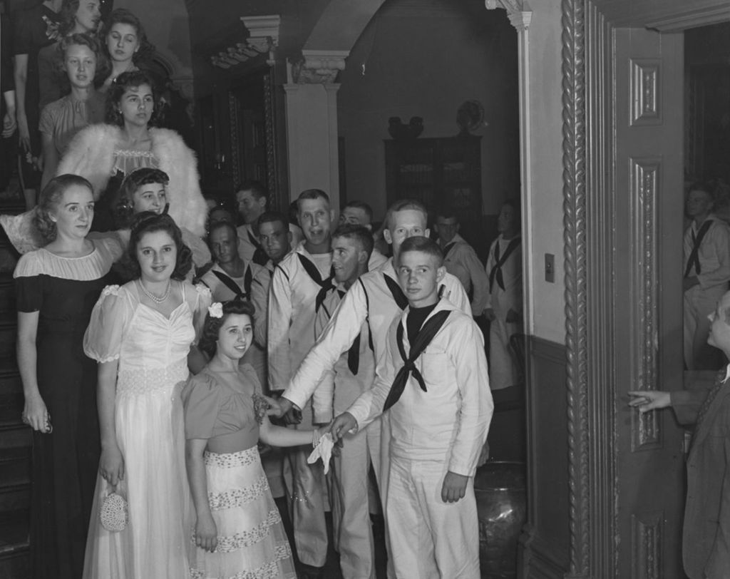 United States Navy sailors in the Hull-House reception area alongside women in formal wear during an "Entertaining the Navy" event