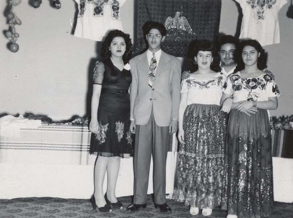 Five people standing in front of a display of Mexican crafts at Hull-House