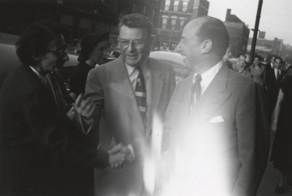 Illinois governor Adlai Stevenson II with Hull-House program director Elaine Switzer and director Russell Ballard on a sidewalk outside Hull-House
