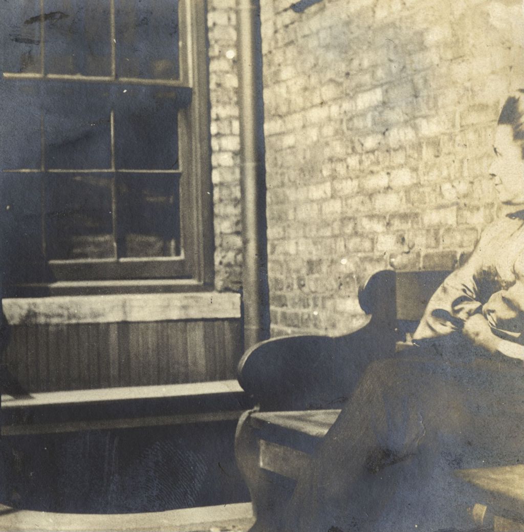 Miniature of Woman sitting on bench against a brick wall at Hull-House